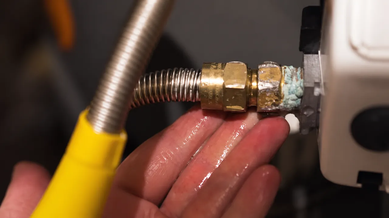 Close view of a water heater fitting and flexible connector